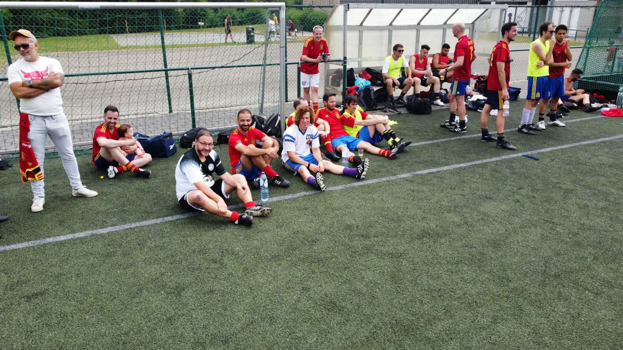 Jugadores y acompañantes descansan y conversan al borde del campo