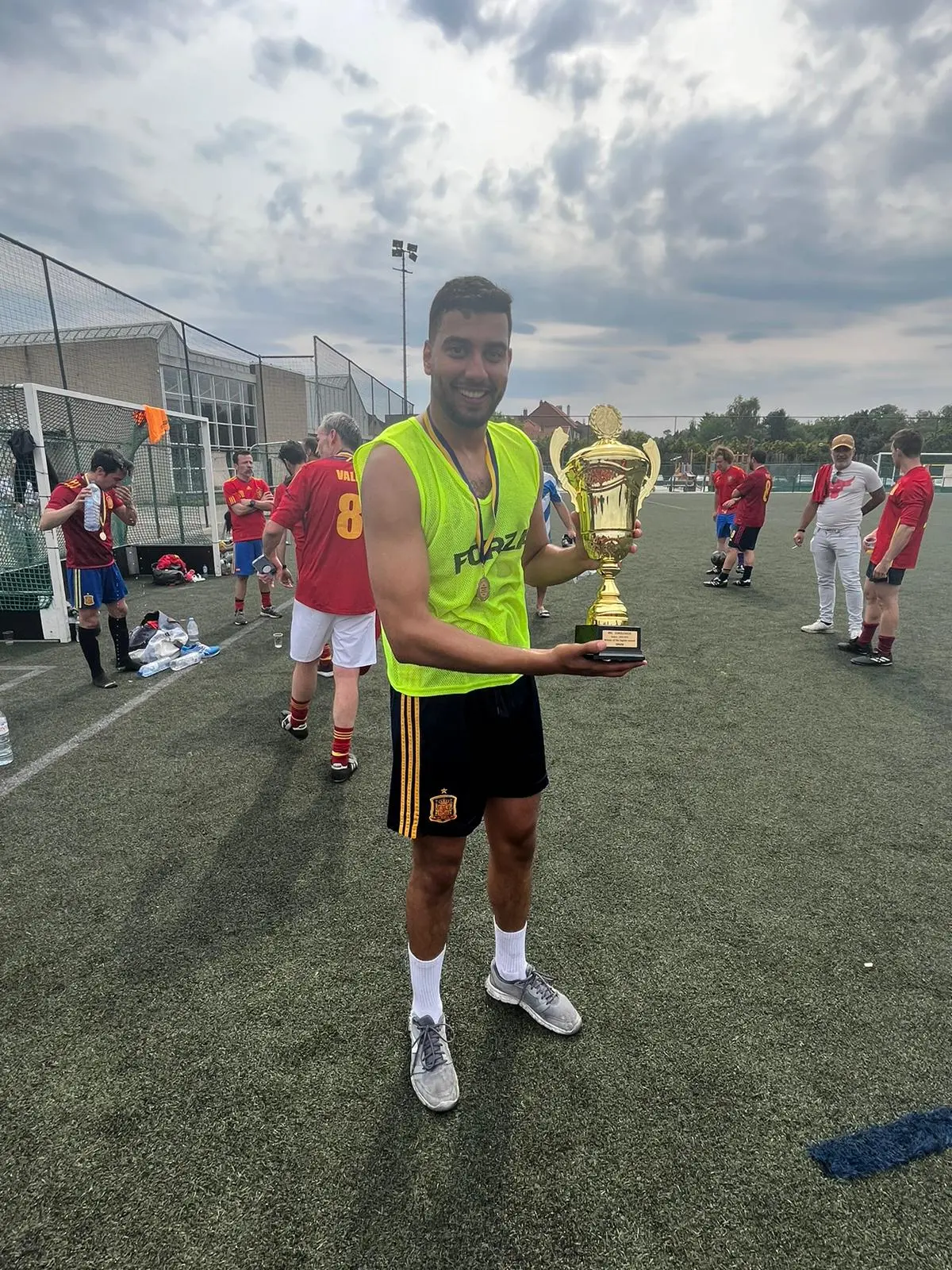 Jugador con peto verde sostiene un trofeo tras el torneo del aniversario